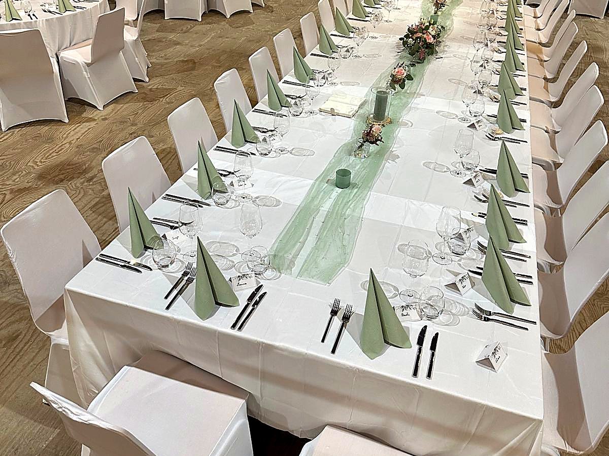 Lange Festtafel mit weißen Hussen, Tüllläufer und Rosengestecken